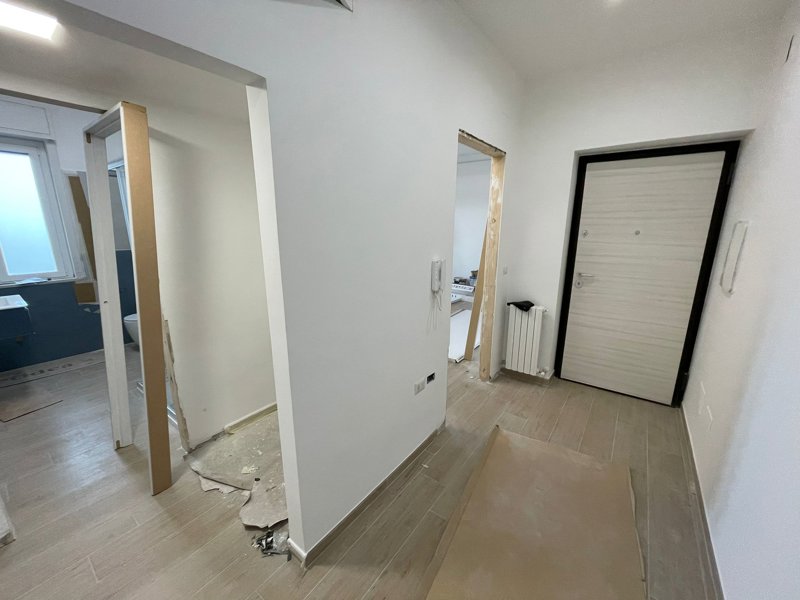Ristrutturazione Appartamento Reggio Calabria – Cantiere ingresso: corridoio distributivo con porta blindata e pavimento effetto legno