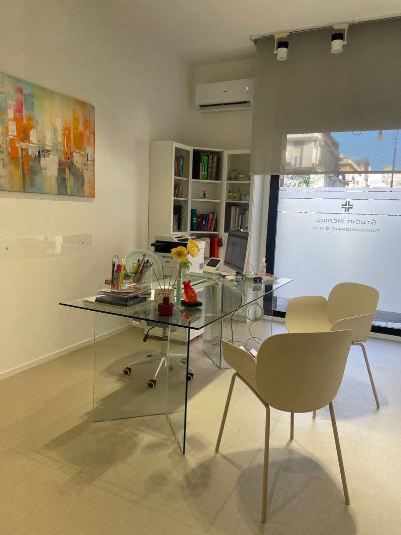 Studio Medico Reggio Calabria – Realizzato: stanza visita con scrivania in vetro trasparente, sedute avorio e quadro astratto