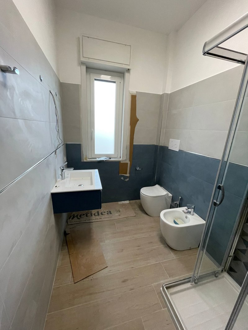 Ristrutturazione Appartamento Reggio Calabria – Cantiere bagno: mobile lavabo blu petrolio e rivestimento bicromatico grigio e blu ardesia